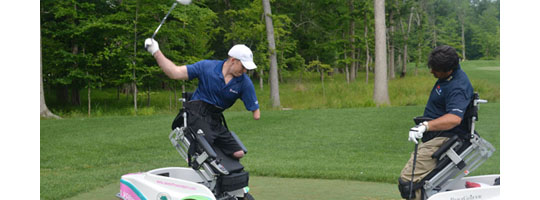 Photo of a man using a specialized assistive golf chair lift while swing a golf club with his left hand he is a triple amputee.